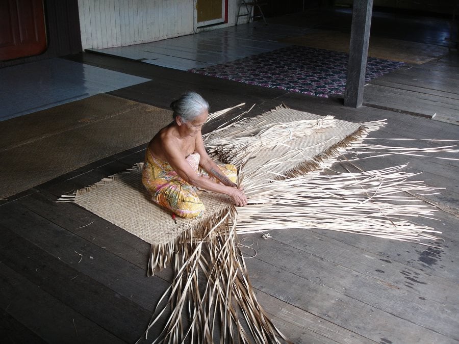 an old native woman weaving a mat in the annah rais long house